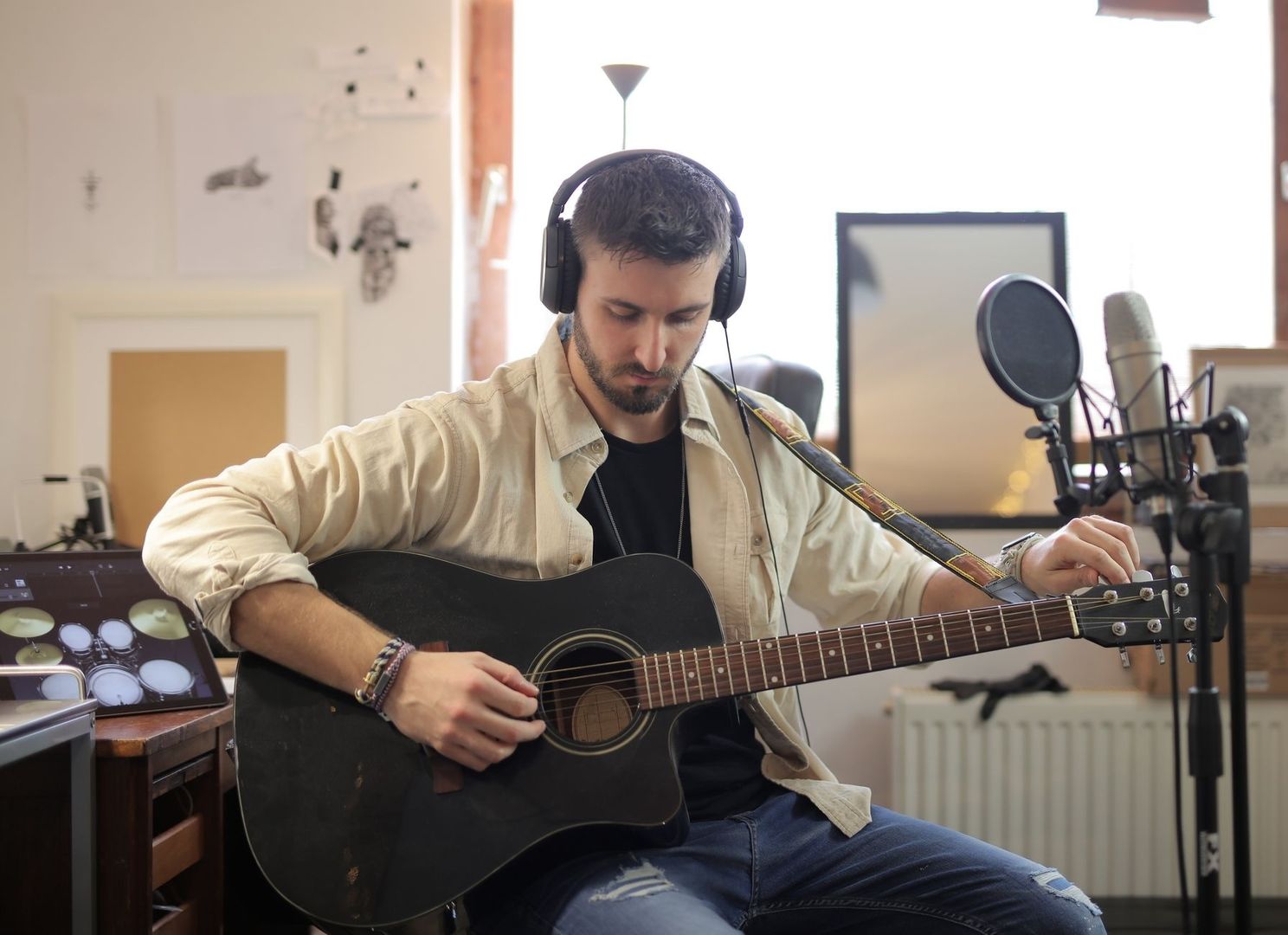 Musiker spelar akustisk gitarr framför en studiomikrofon